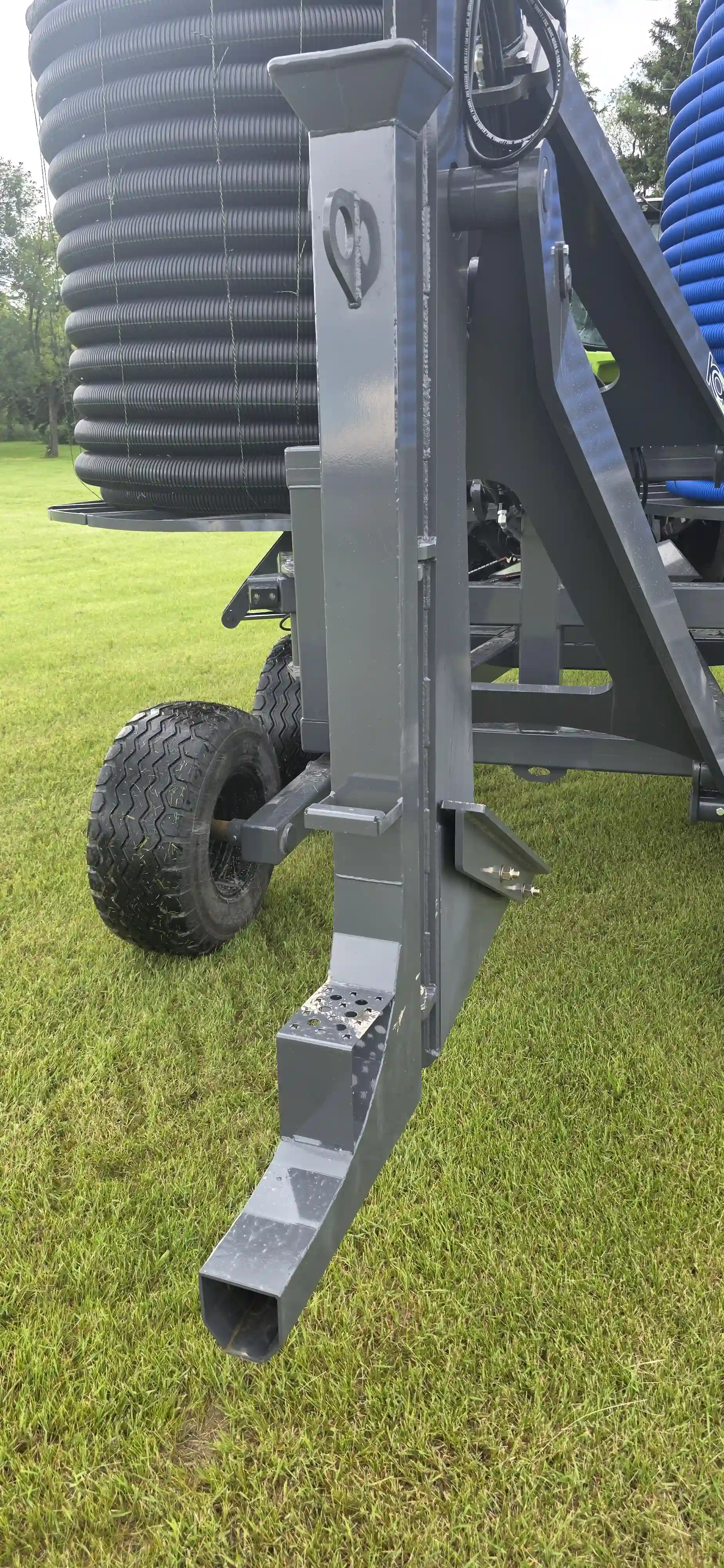 Close-up of an interchangeable metal tile plow boot showing the mechanism feeding plastic drainage pipe into the ground at a precise depth.