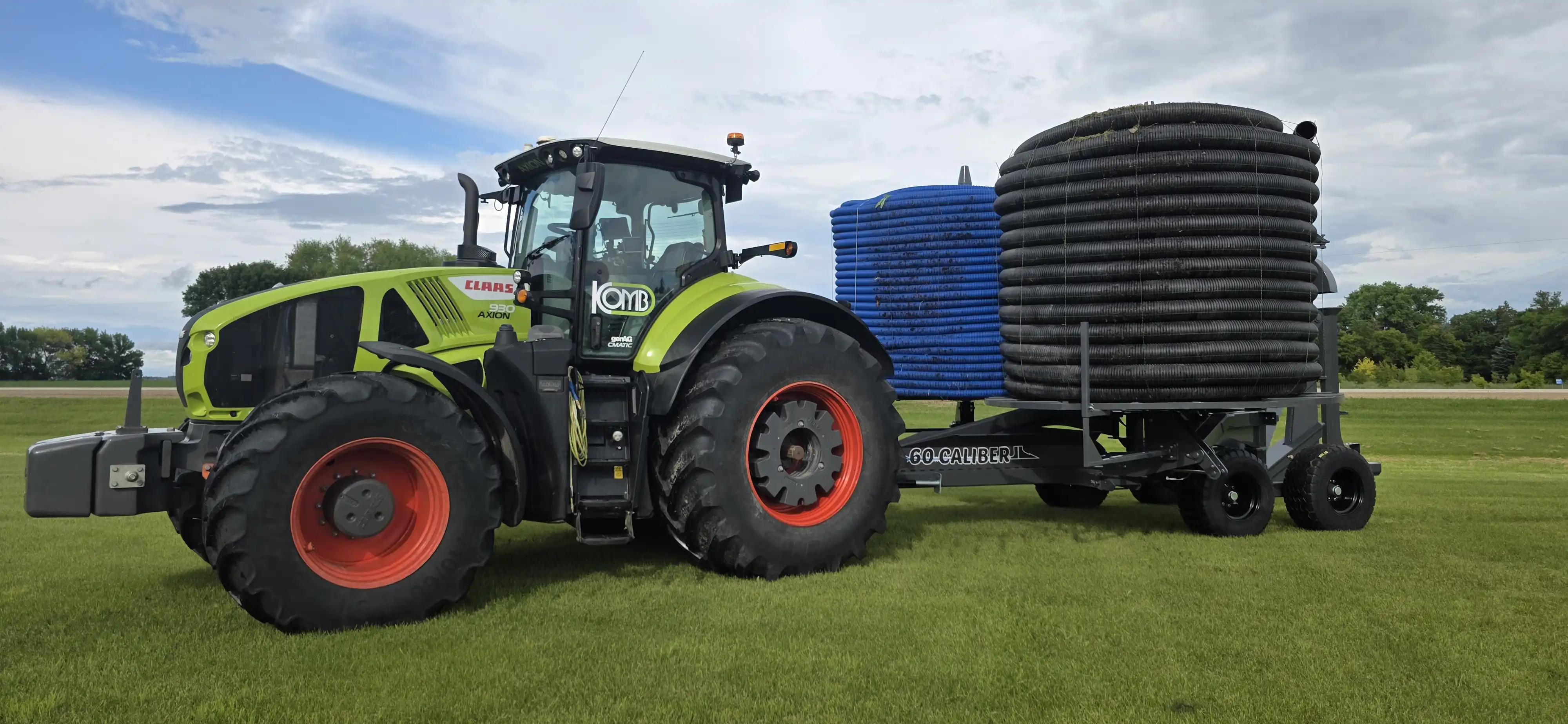 Side profile view of a heavy-duty 60 Caliber agricultural tile plow fully loaded with massive coils of blue plastic drainage pipe on its dual reels.