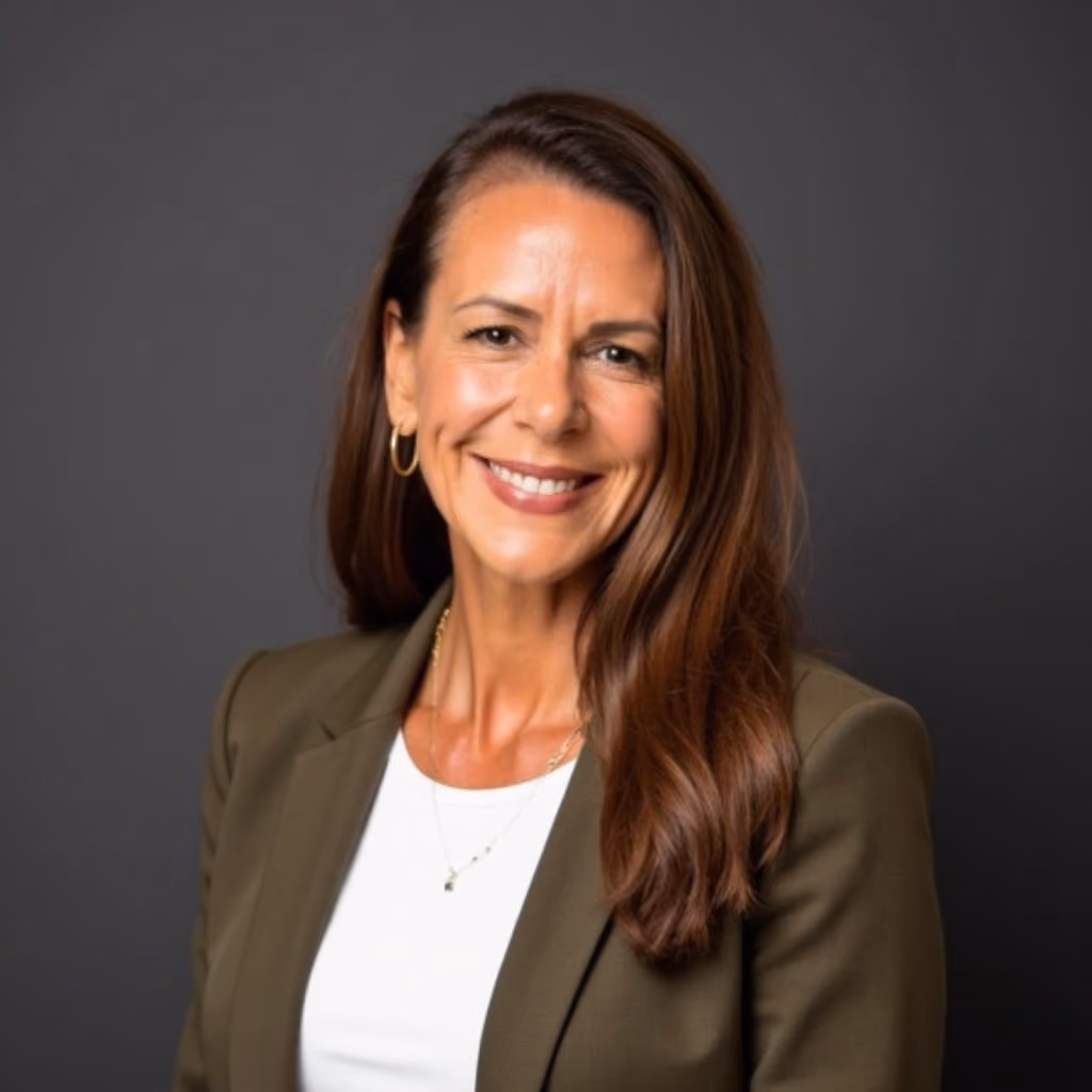 Smiling woman with long brown hair wearing an olive blazer and white top against a gray background.