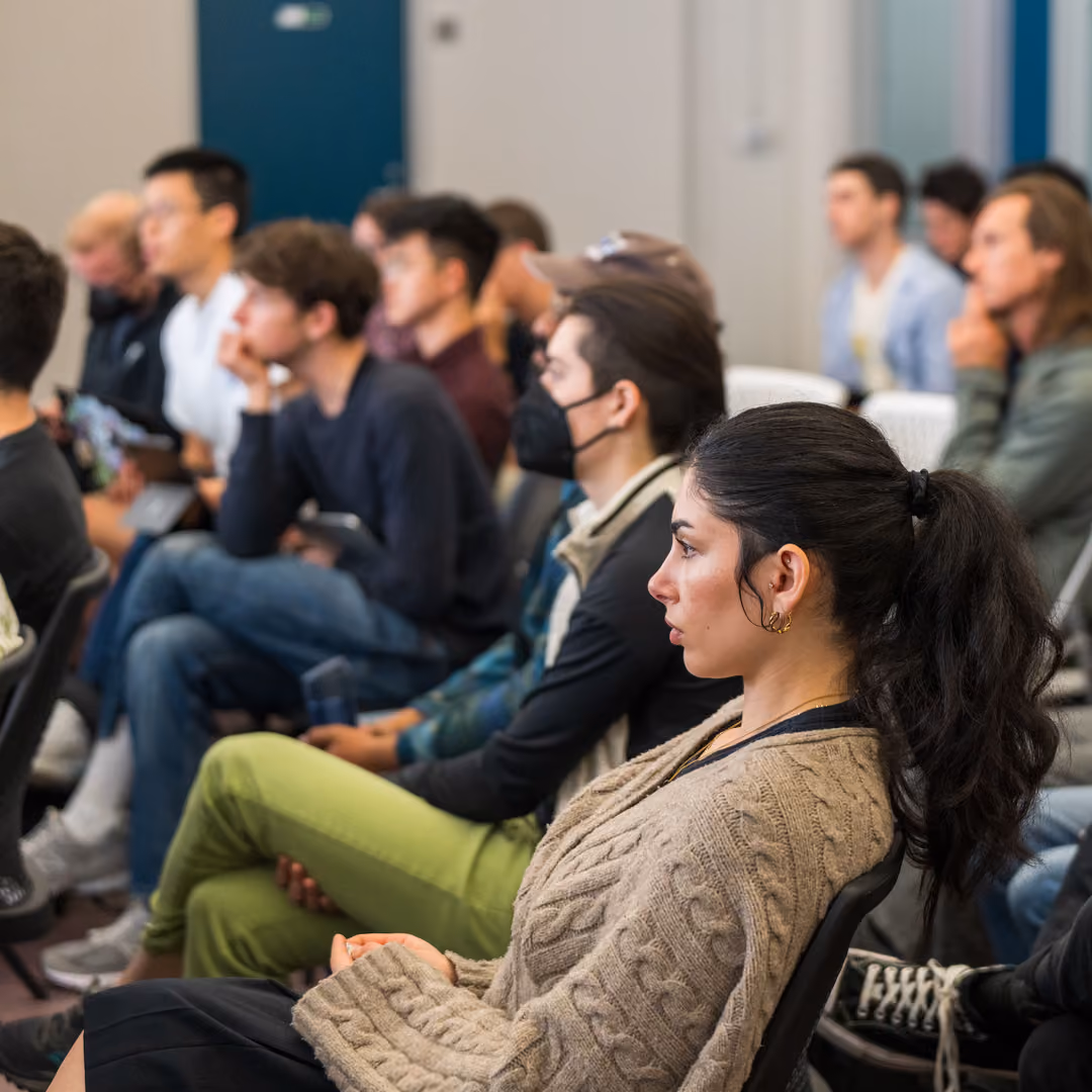 A diverse group of people seated attentively in a classroom or seminar setting.