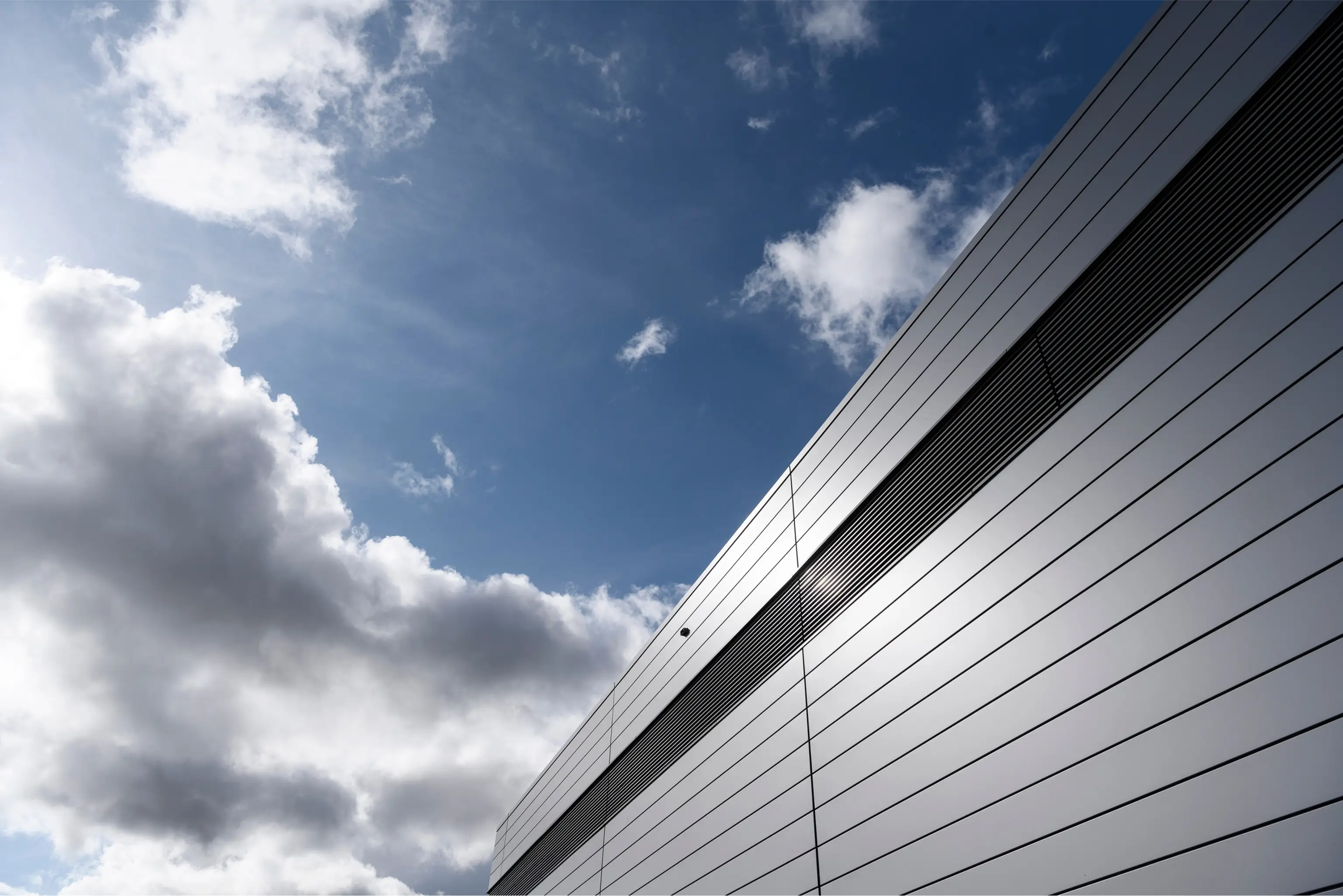 Moderne Gebäudefassade mit horizontalen Linien unter einem bewölkten Himmel.