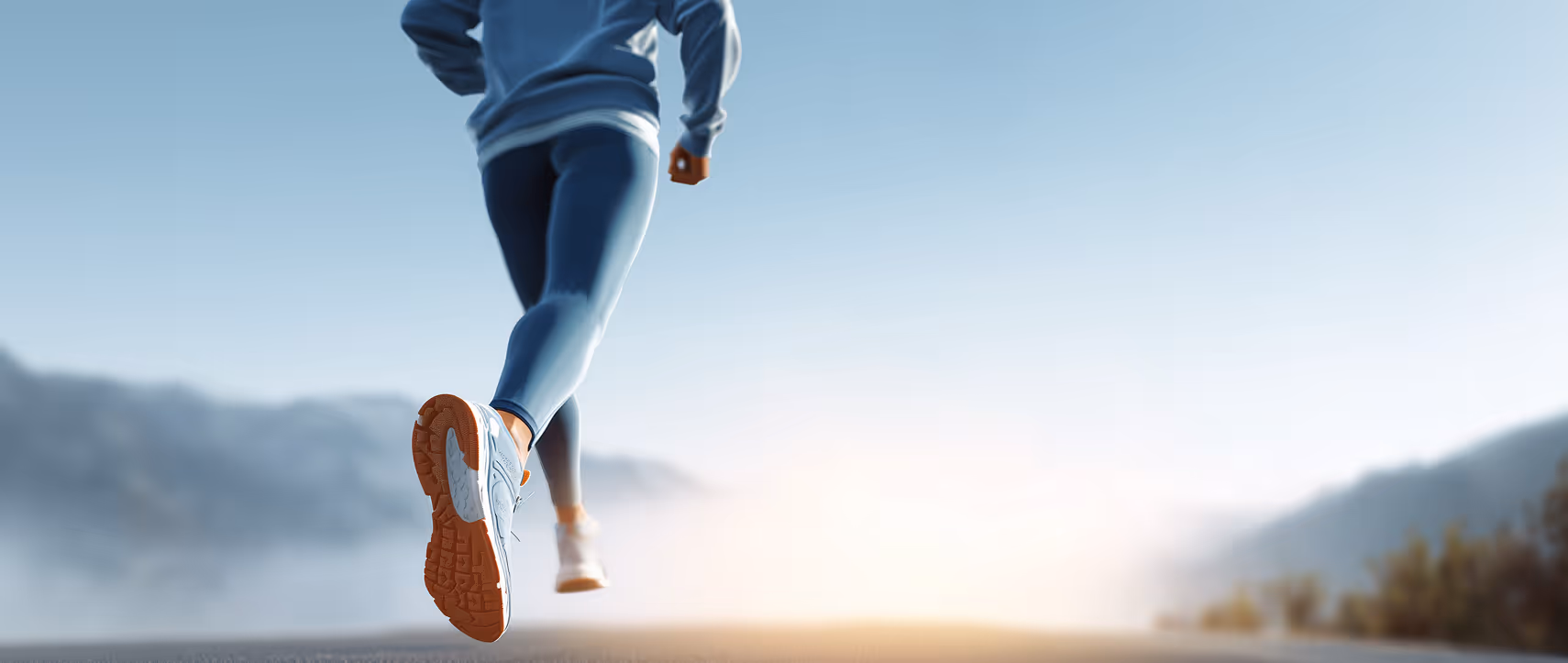 Rückansicht eines Läufers in Sportkleidung, der bei Sonnenaufgang auf einer Bergstraße joggt.