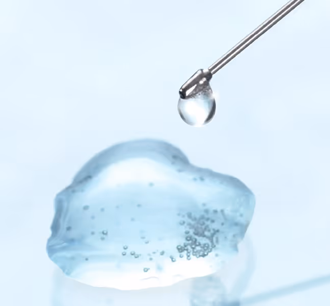 Eine Pipette tropft eine klare Flüssigkeit auf eine blaue Gelkugel.