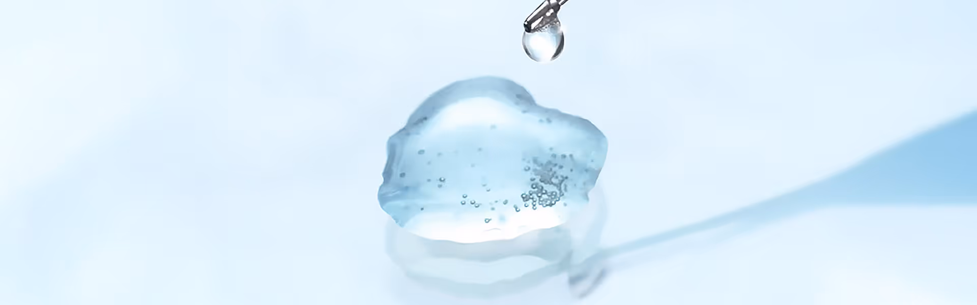 Eine Pipette träufelt eine klare Flüssigkeit auf ein biegsames transparentes Gelpolster.