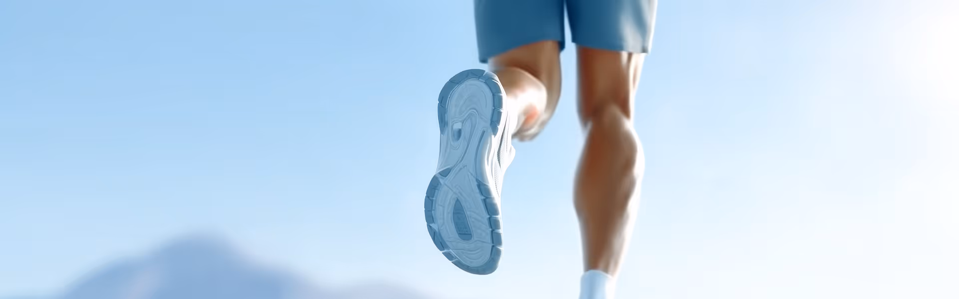 Ein Läufer in blauen Shorts und weißen Schuhen von hinten mit Fokus auf die Schuhsohle.