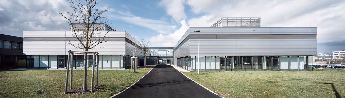 Modern Bürogebäude mit Glasfronten und Metallverkleidung an einem bewölkten Tag.