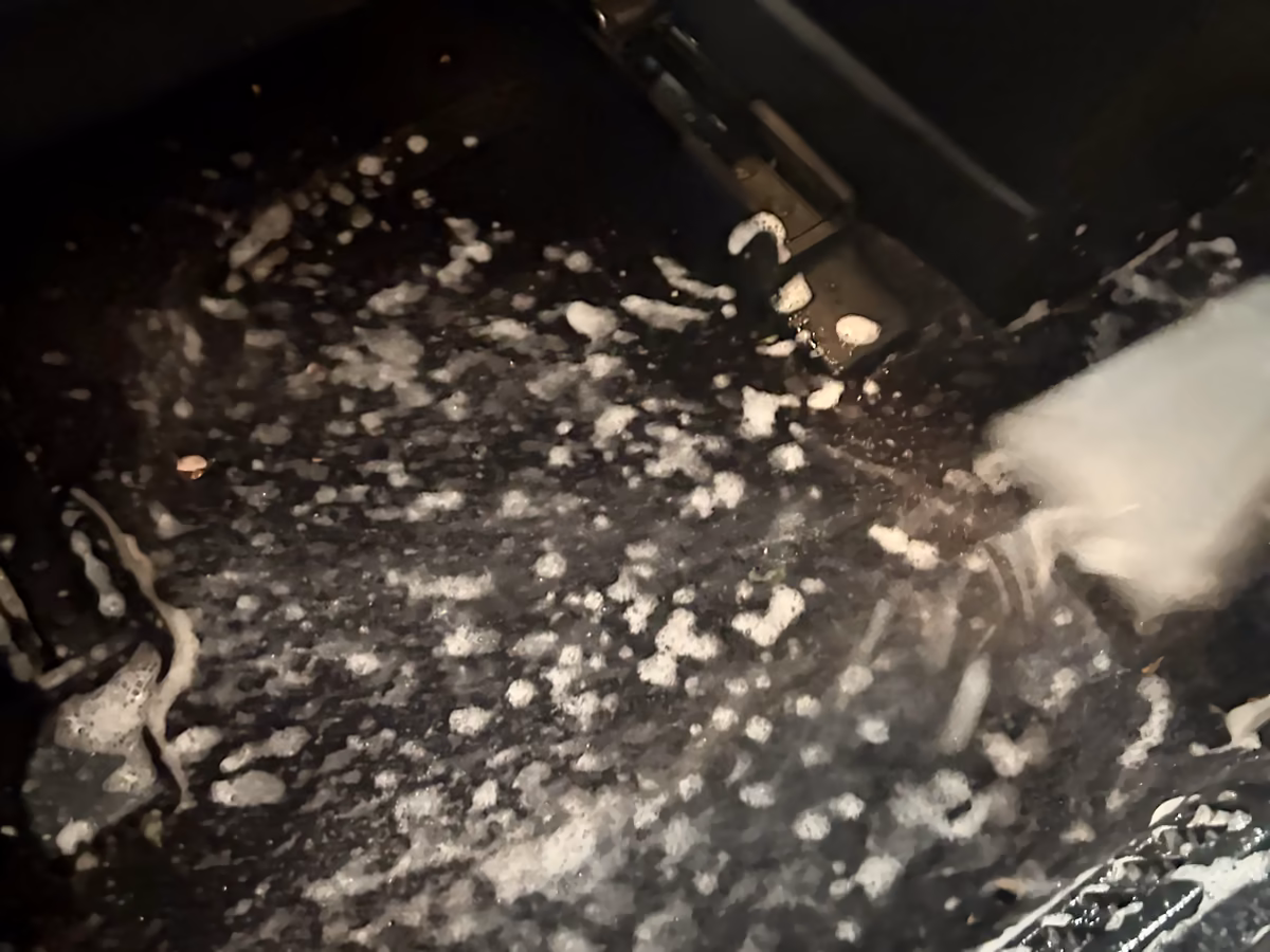 Injection du produit de shampouinage à la buse sur la moquette du plancher d'une voiture, atelier Bingo'z à Paris 15