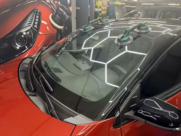 Pose d'un pare-brise maintenu aux ventouses sur une voiture rouge, atelier Bingo'z Paris 15
