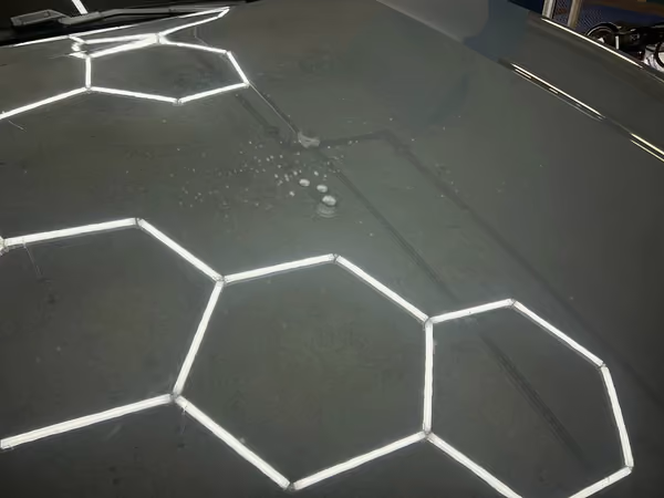 Gouttes d'eau qui perlent sur une carrosserie traitée, effet hydrophobe de la protection céramique
