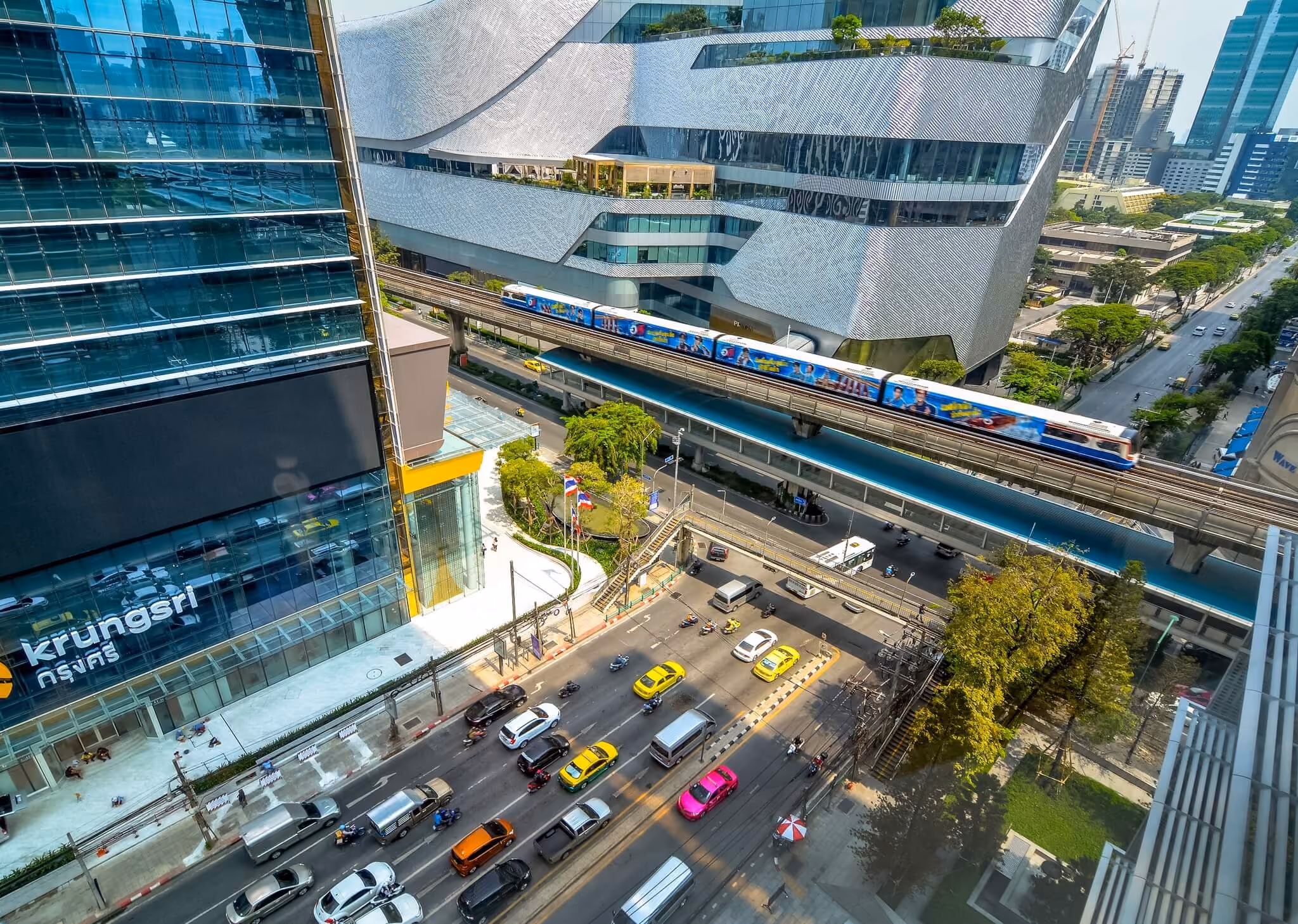 An aerial view of a Bangkok intersection with a BTS train passing a Krungsri building