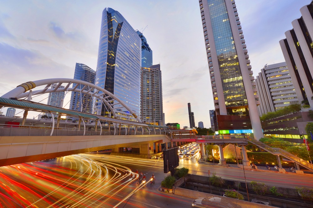The Sathorn Road bridge at dusk, with light trails running beneath surrounding office towers
