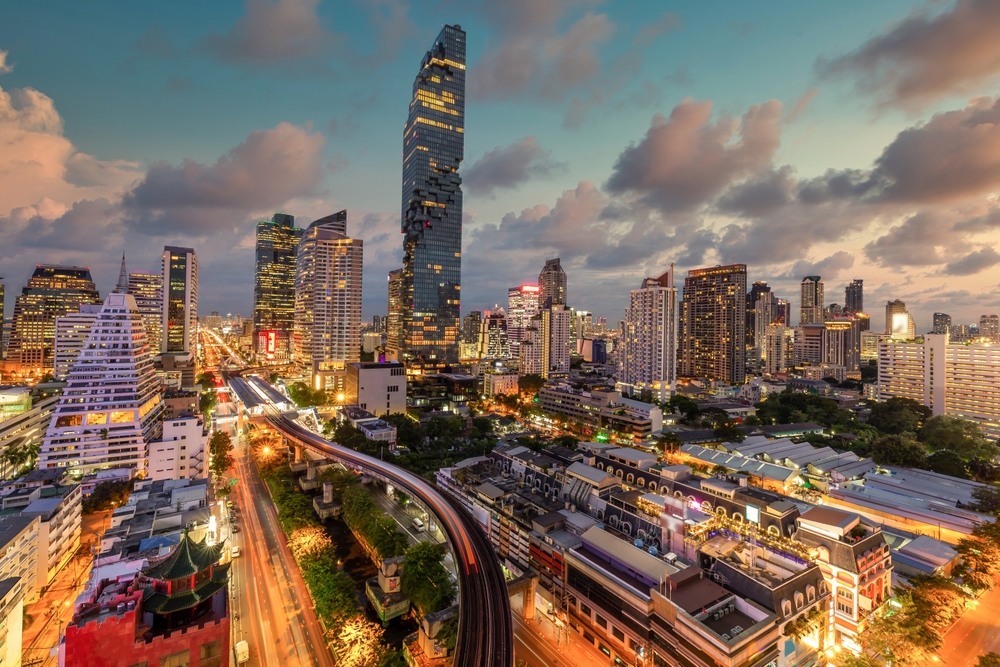 The Silom financial district at dusk, with the MahaNakhon tower above lit streets and the BTS line