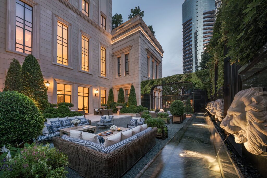An outdoor terrace at 98 Wireless at dusk, with sofa seating beside a classical stone facade