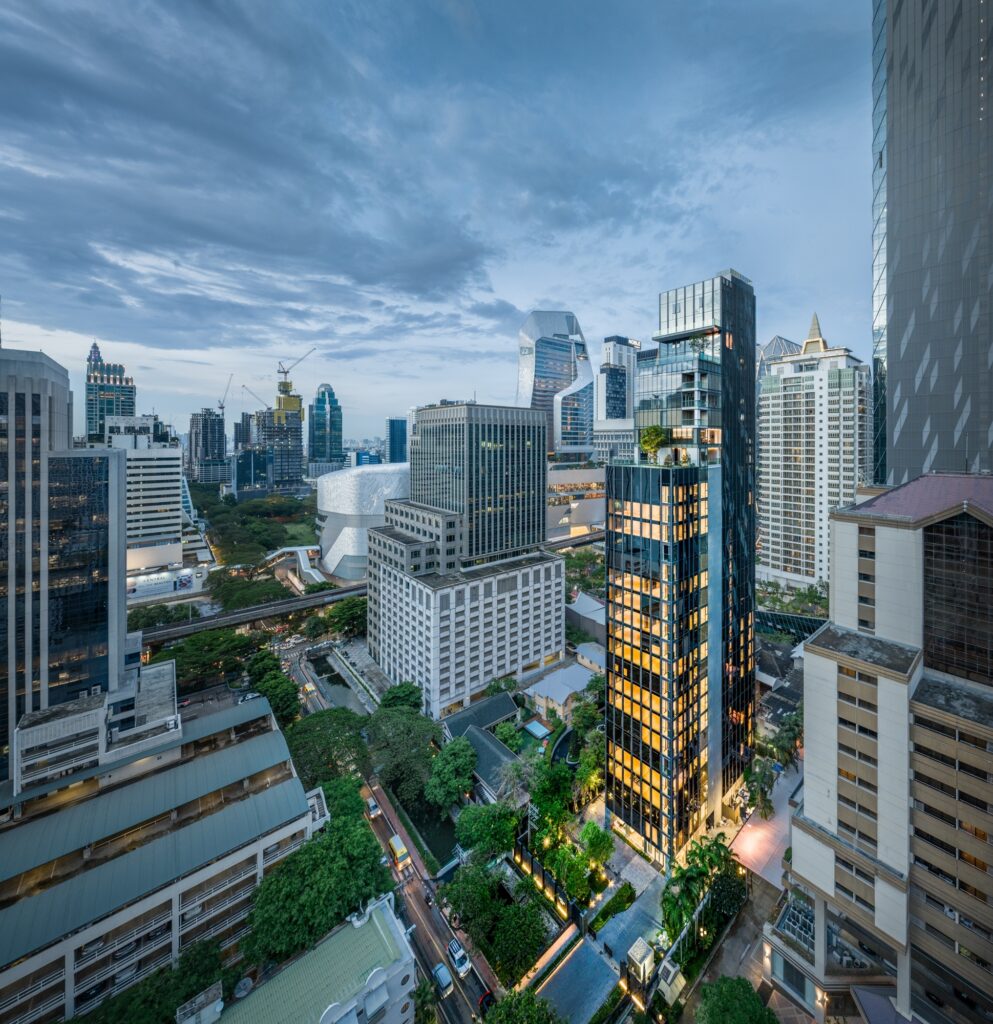 A render of the Tonson One Residence tower rising among central Bangkok buildings and trees