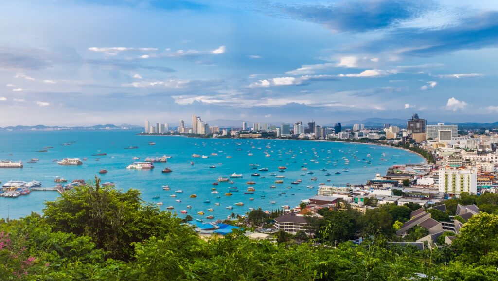 Pattaya bay in daylight, with boats moored off the curved beachfront skyline