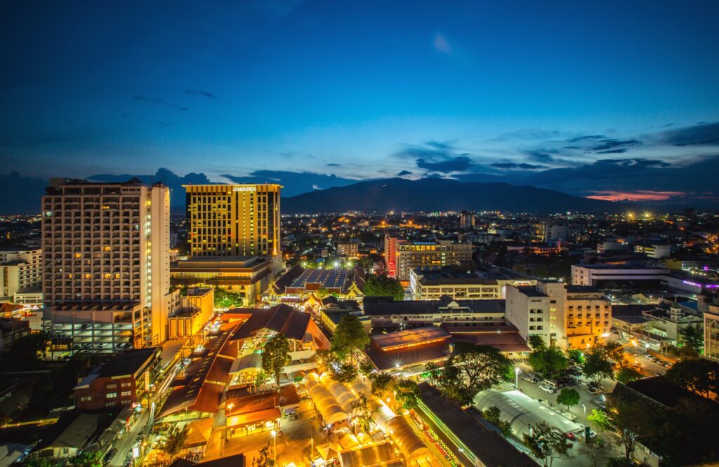 Chiang Mai at night, its lit streets and low buildings backed by mountains