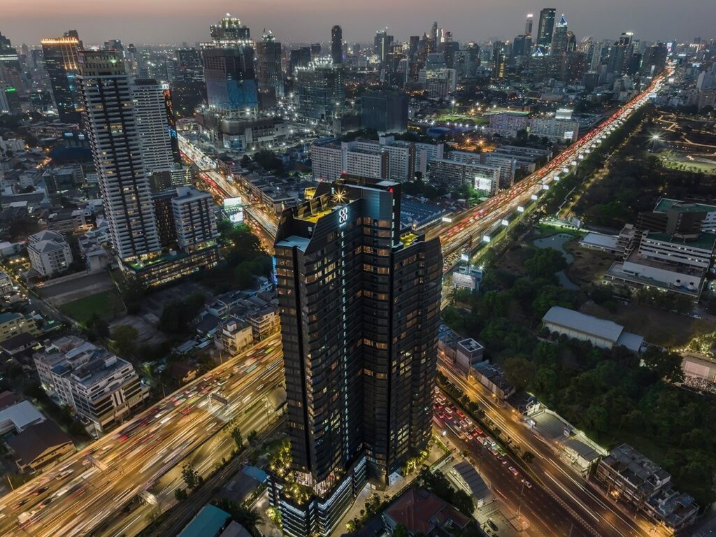 The Coco Parc tower on Rama IV Road at dusk, rising above the surrounding rooftops