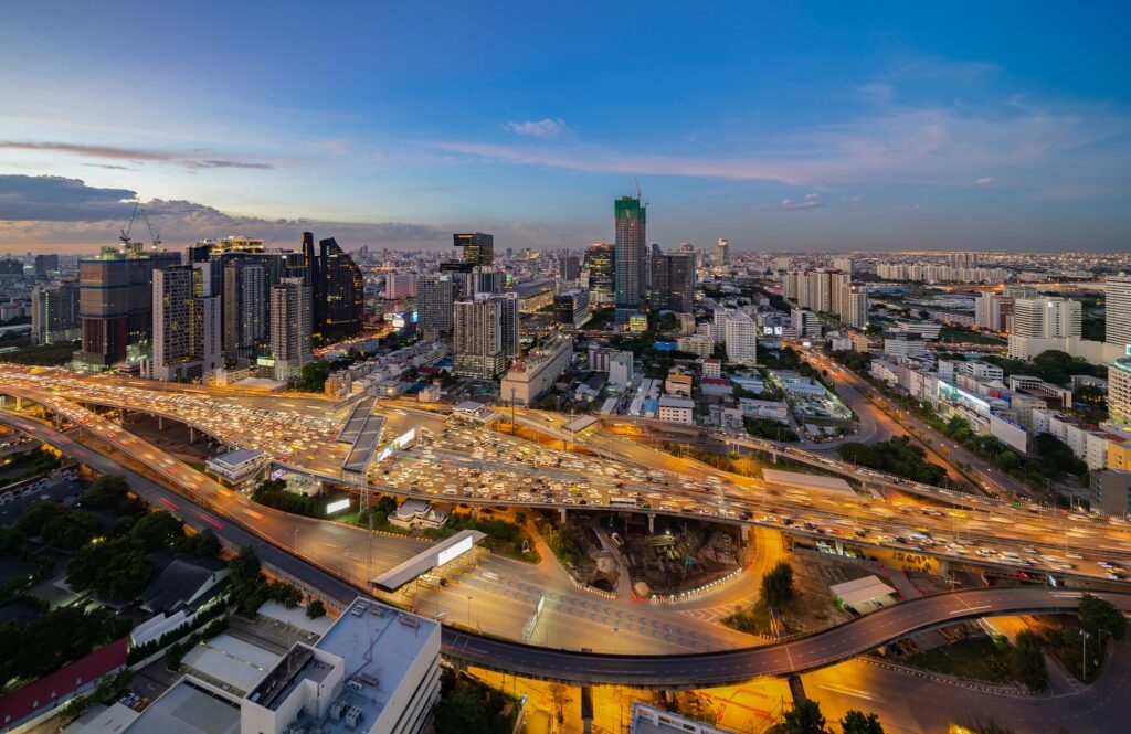 An aerial view of the Rama IX and Ratchada district at dusk, with the expressway curving through it