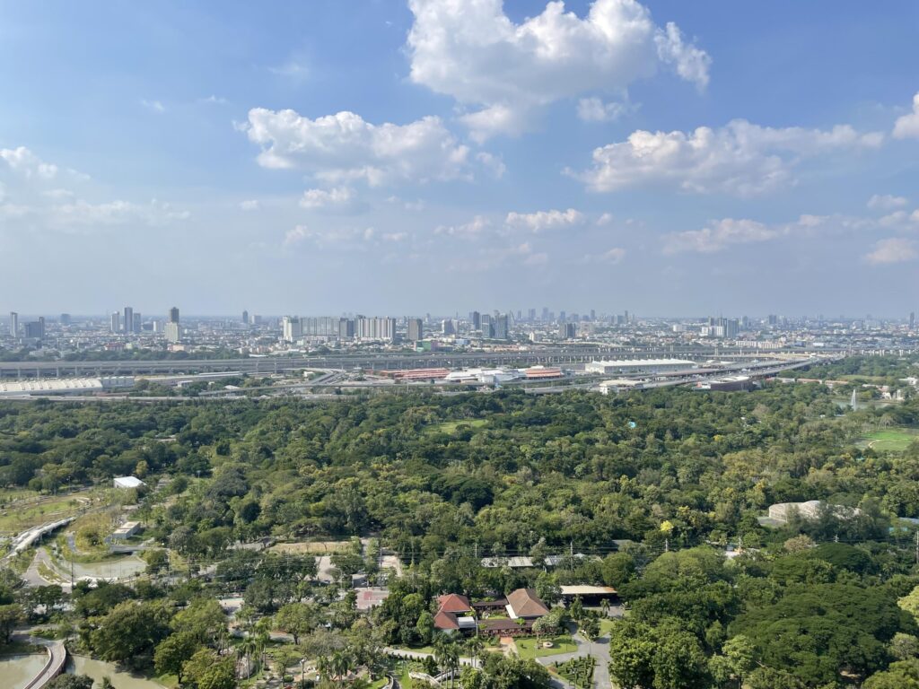 Green parkland near Lat Phrao with the Bangkok skyline low on the horizon