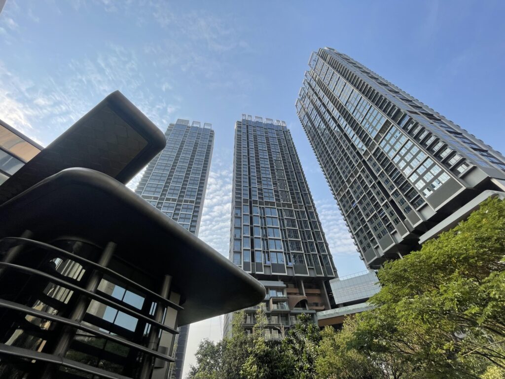 Looking up at the curved towers of The Forestias by MQDC, framed by a dark canopy