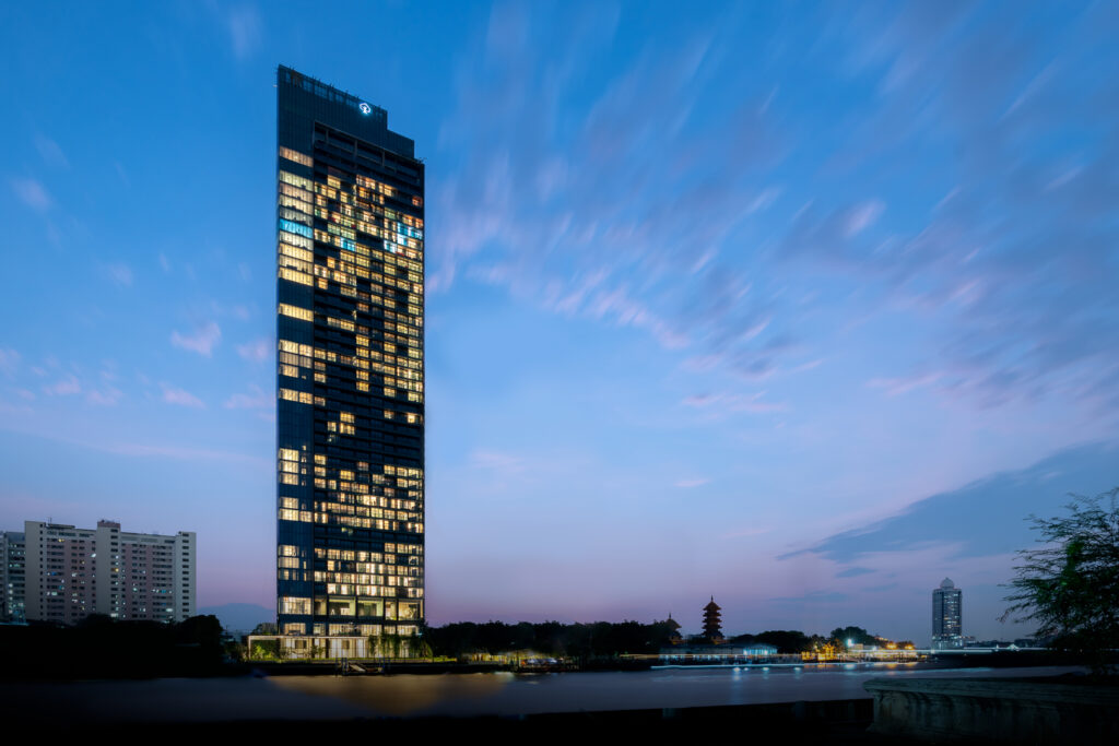 The Banyan Tree Residences Riverside tower lit at dusk beside the Chao Phraya