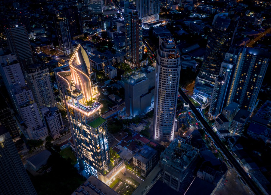 A night aerial over Thonglor, with the lit crown of the Laviq Sukhumvit 57 tower