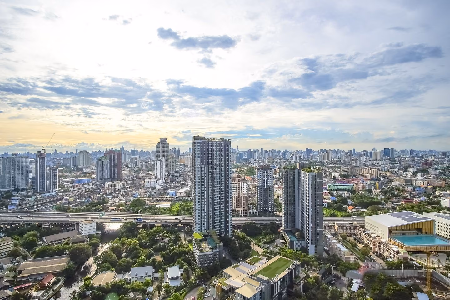 Wide daytime panorama of On Nut condo towers, expressway and low-rise sprawl under cloud