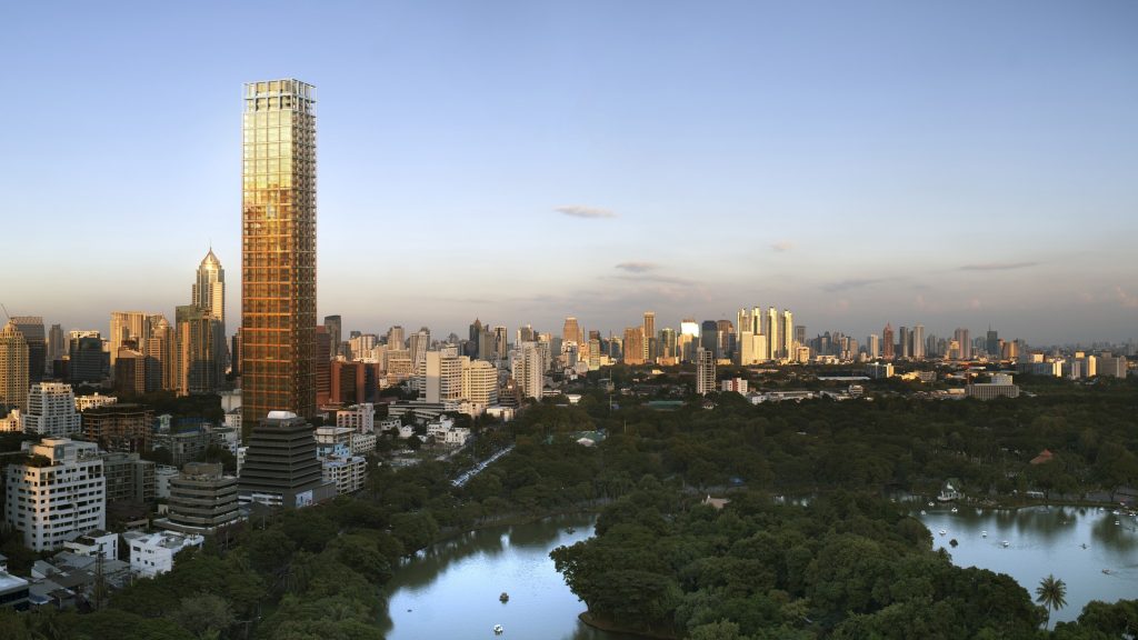Golden-lit tower rising above a park's lake and treetops at dusk, city skyline behind