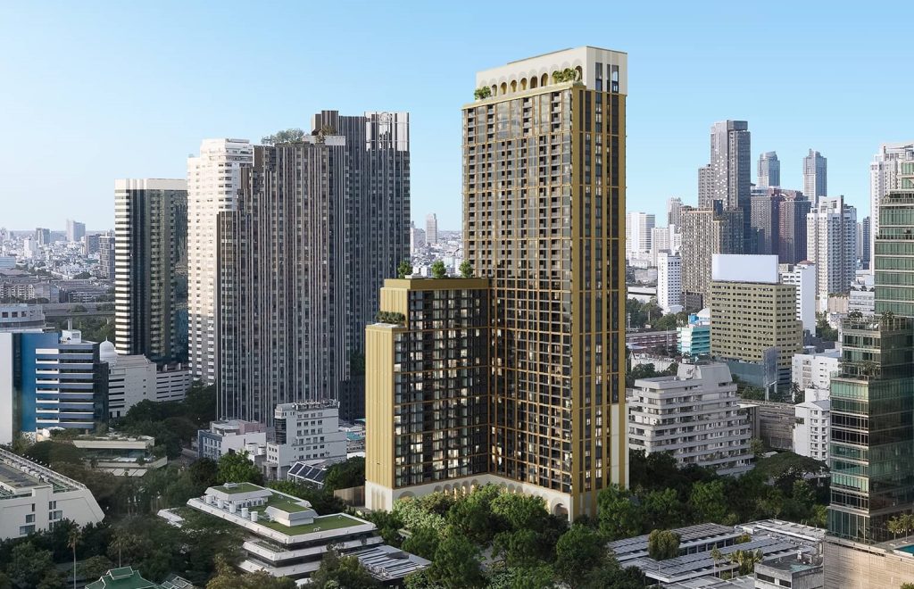 Pair of tall cream-toned towers rising over leafy low-rise neighbourhood, blue sky
