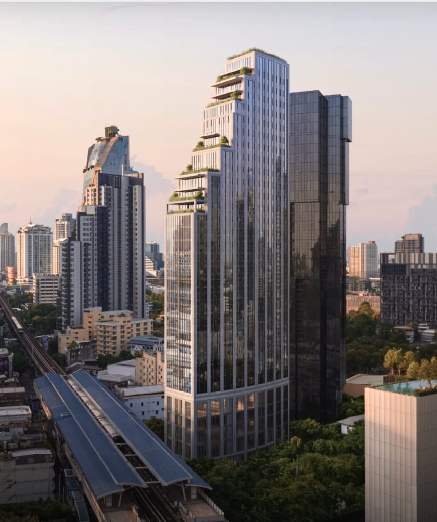 Angular high-rise at sunset among Thonglor towers, with the elevated BTS line curving below