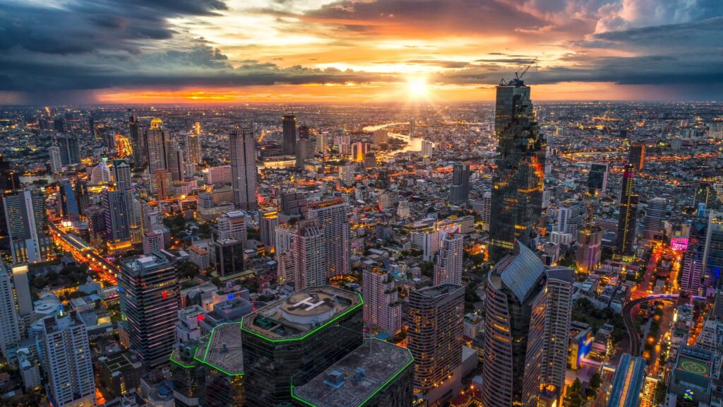 Bangkok skyline at sunset seen from above, the MahaNakhon tower among lit high-rises