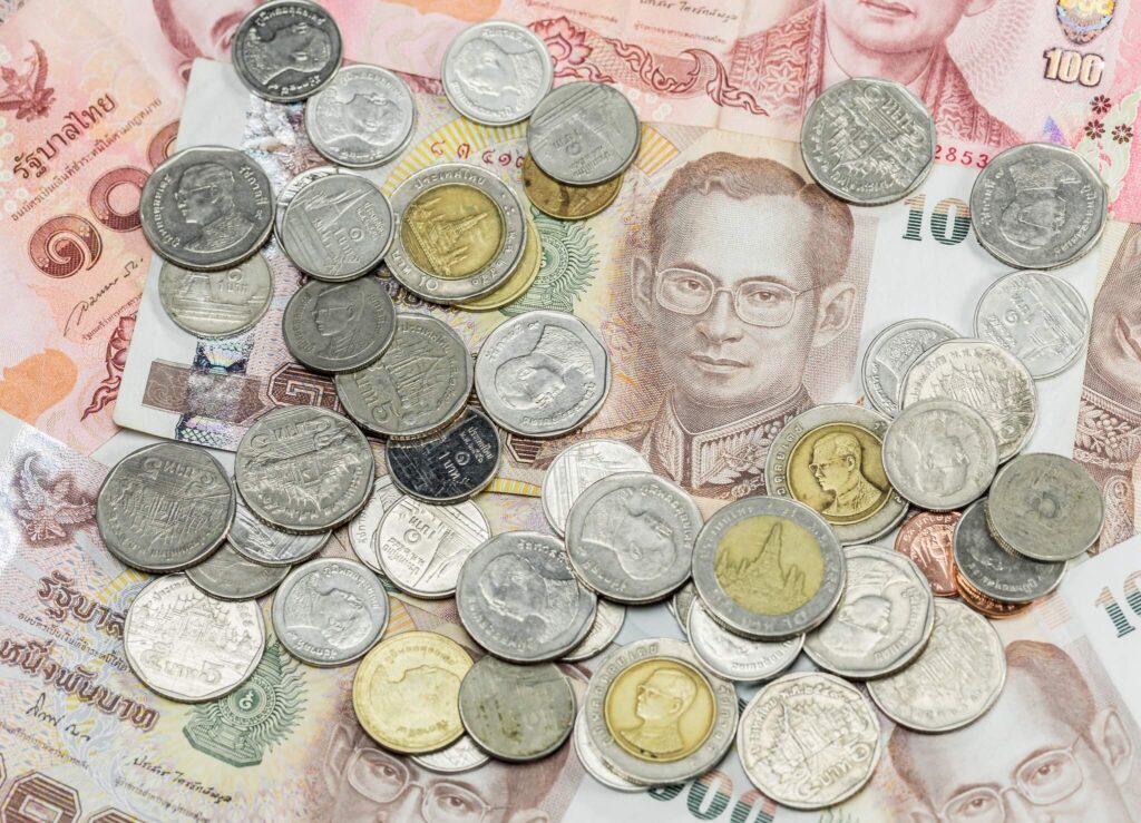 Thai baht banknotes scattered with silver and gold baht coins
