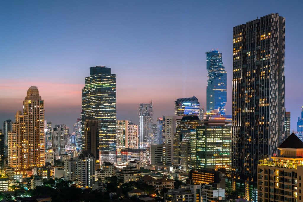 Bangkok high-rises at dusk, the MahaNakhon tower lit blue among lit office and condo towers