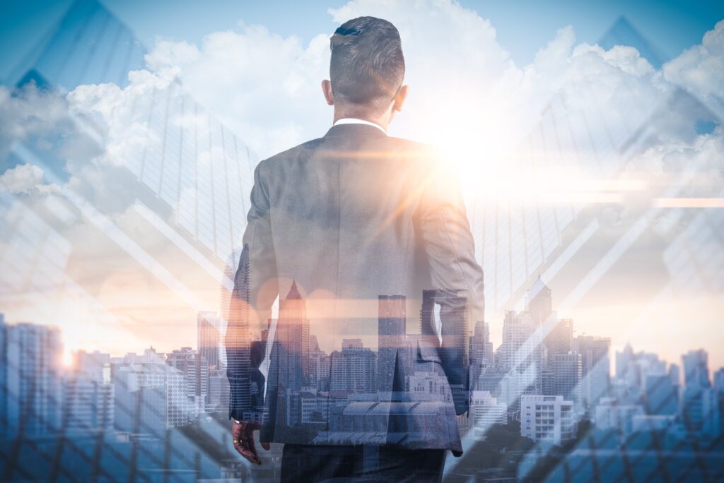 Double exposure of a man in a suit looking out over a city skyline in bright sunlight
