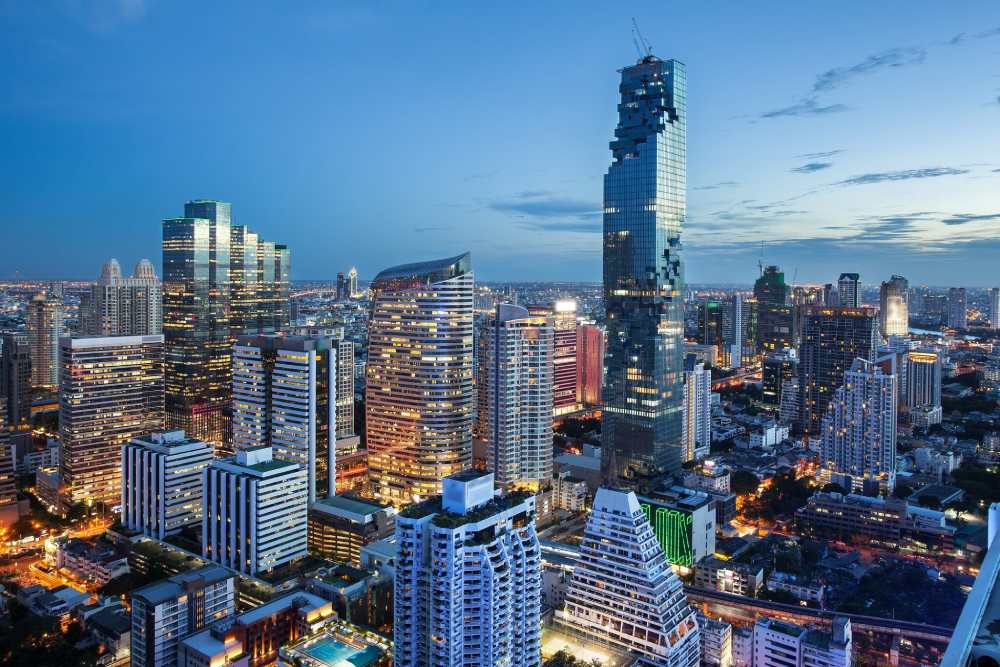 Bangkok skyline at dusk, the pixelated MahaNakhon tower rising above lit condo towers