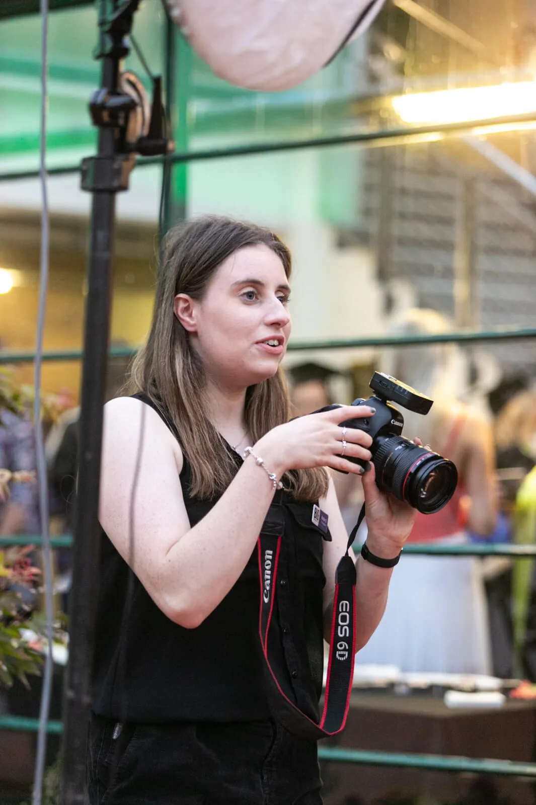 Woman holding a DSLR camera beneath event lighting equipment.