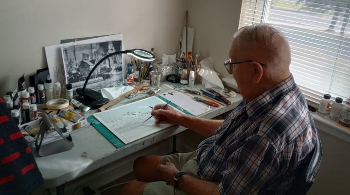 Frank Slim beginning a new painting project at his work desk