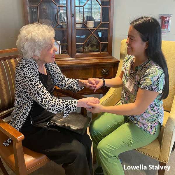 Resident and caregiver Lowella grasping hands and chatting together