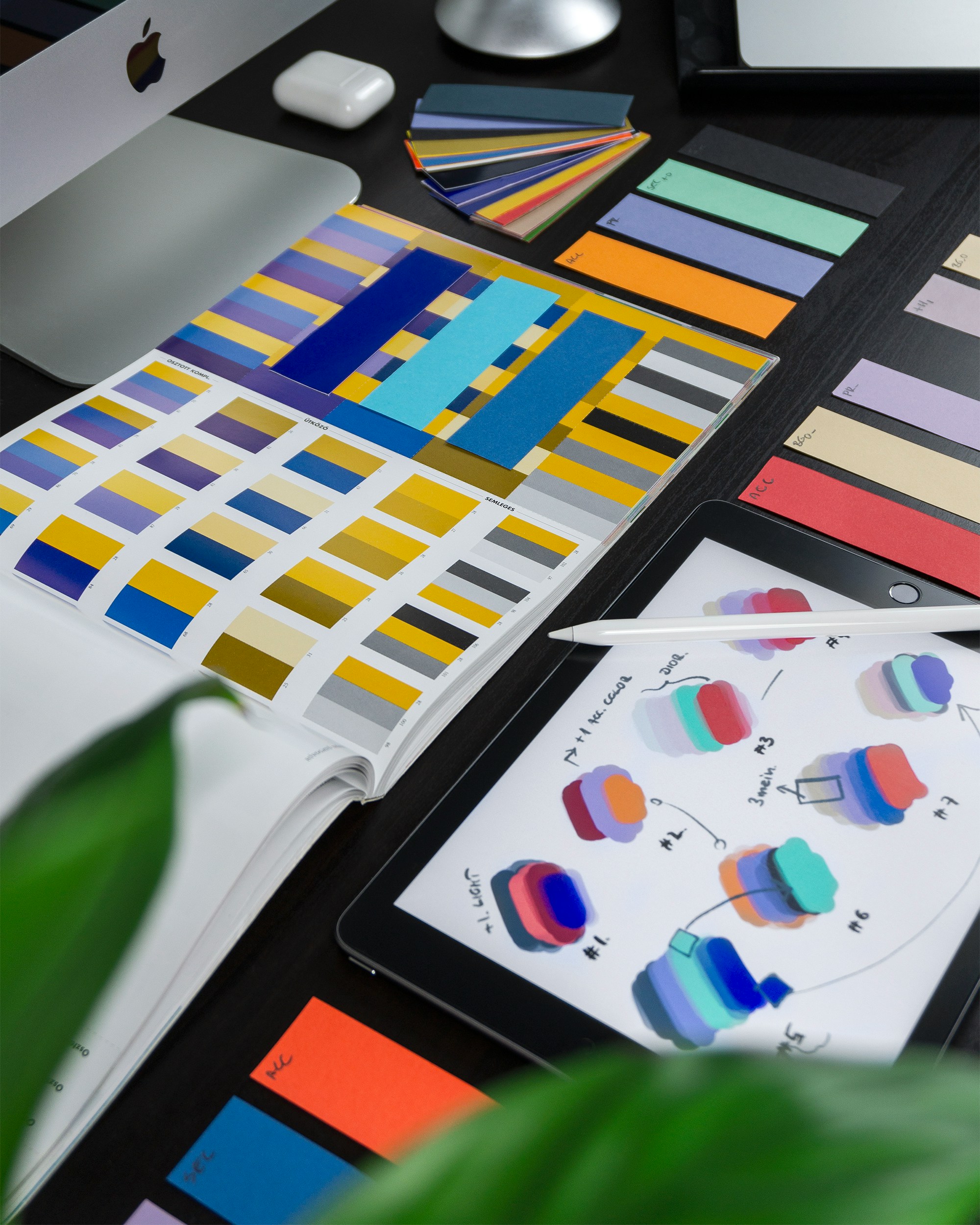 Design workspace with color swatches, an open color guide, and a tablet displaying color concepts.