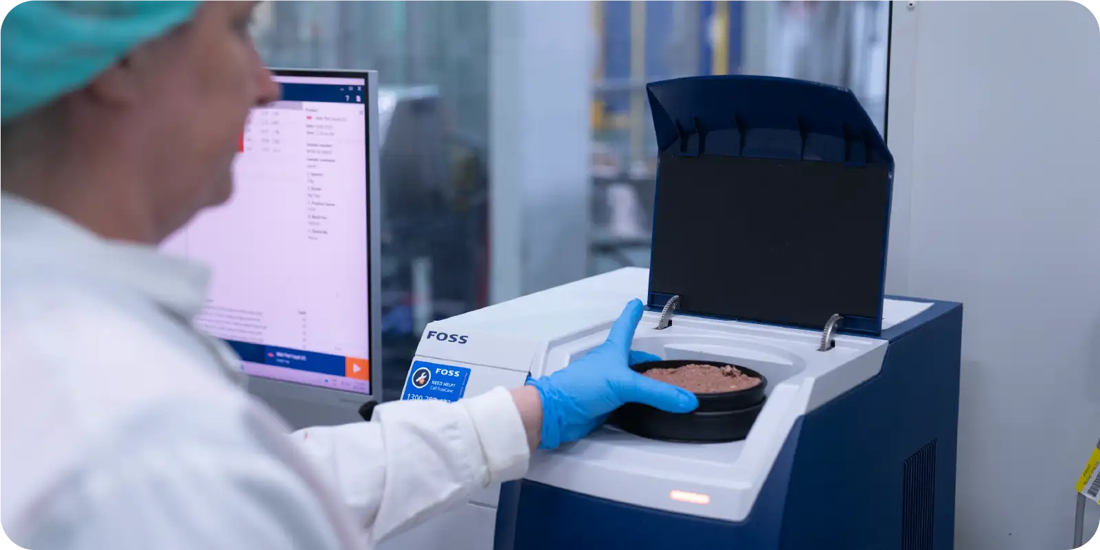 Lab staff in white labcoat and hair net using FOSS machine in Leading Raw production facility