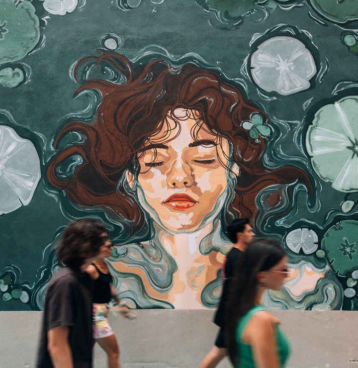 Students walking past a painted mural in the piazza