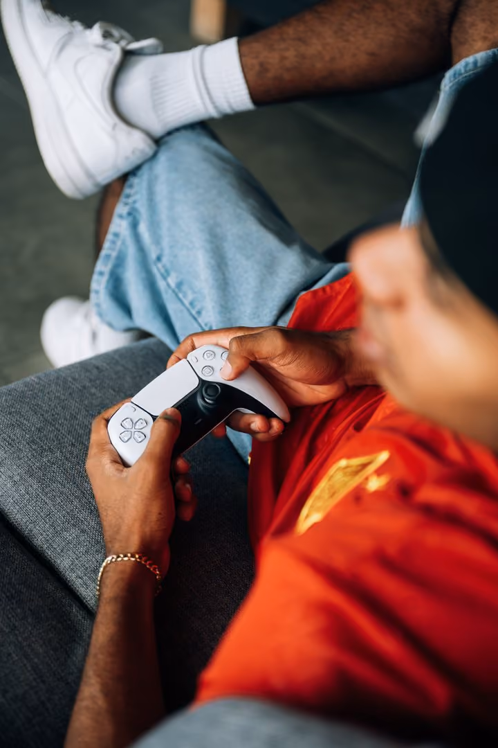 A student holding a games controller on the sofa