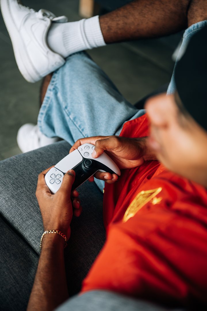 A student holding a games controller on the sofa