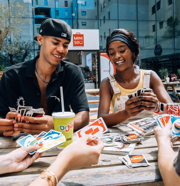 Students playing cards together outside in the piazza