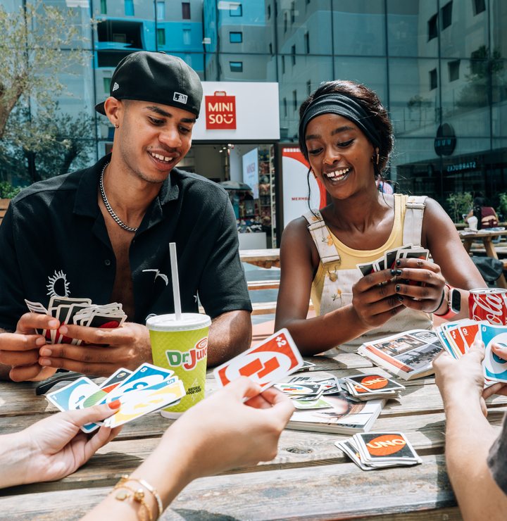 Students playing cards together outside in the piazza