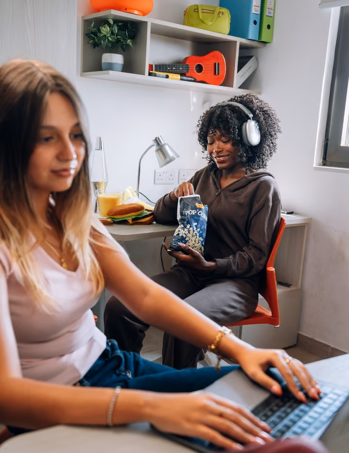 A student working on a laptop at the desk in her room