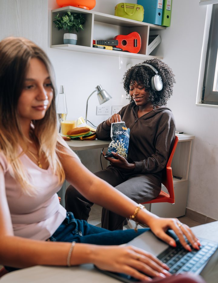 A student working on a laptop at the desk in her room