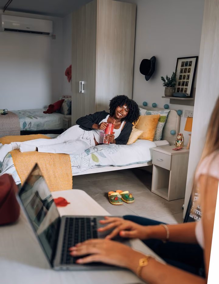 A student working on a laptop from her bed