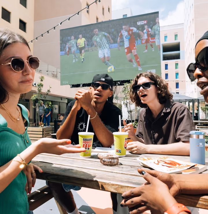 Students watching football together on an outdoor screen