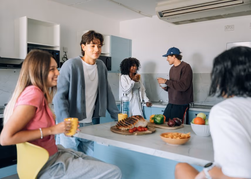 Students talking together over food around a shared kitchen island